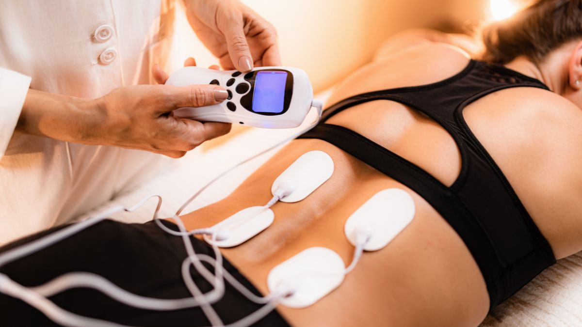 Egy nő hátán TENS készülék elektródái láthatók, miközben kezelést kap.