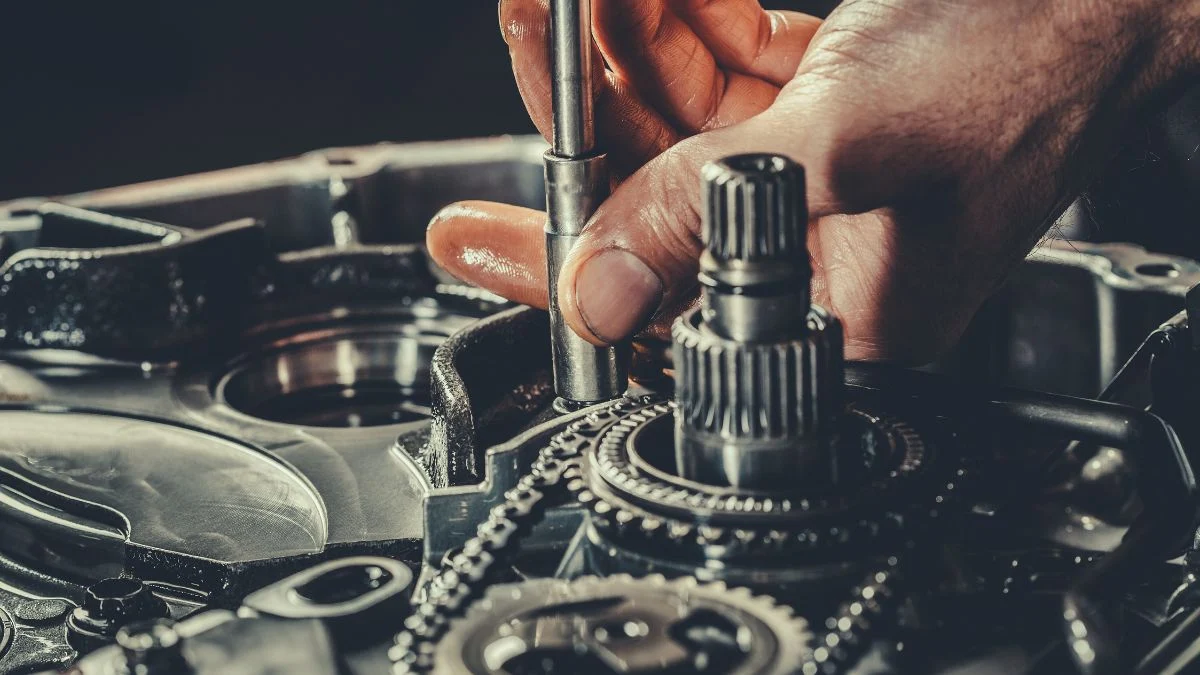 Kéz, amely egy motor alkatrészén dolgozik, a CVVT technológia bemutatásához kapcsolódóan.