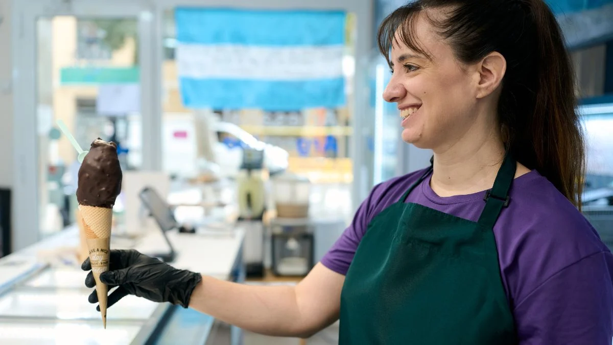 Egy nő egy csokis fagyit tart a kezében, mosolyogva a fagylaltozóban.