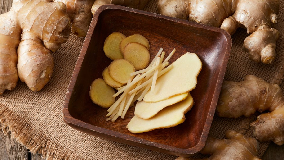 Friss gyömbérgyökerek és vékonyra szeletelt gyömbérdarabok egy tálban.