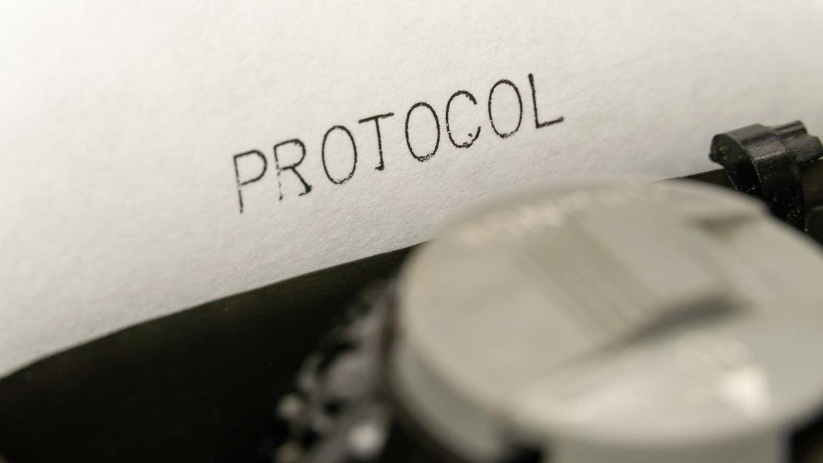 Egy írógép papírján a 'PROTOCOL' szó látható, a gép részleteivel.