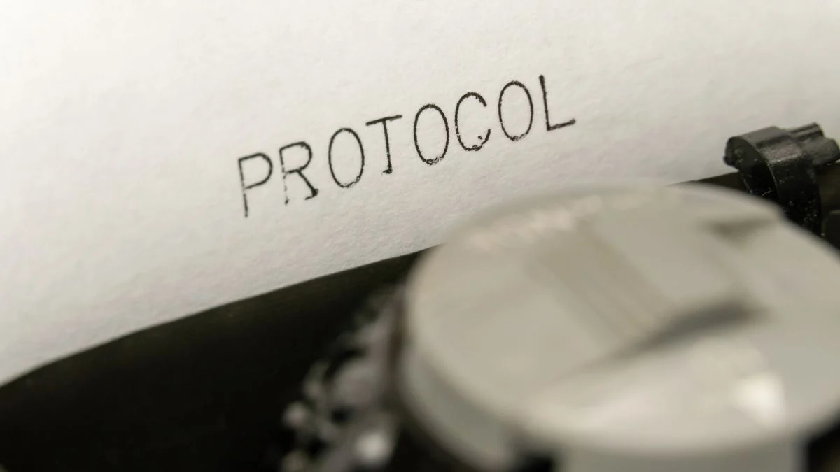 Egy írógép papírján a 'PROTOCOL' szó látható, a gép részleteivel.