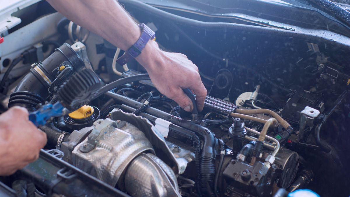Egy kéz autómotor alkatrészeit szereli, hangsúlyozva a technológiai precizitást.