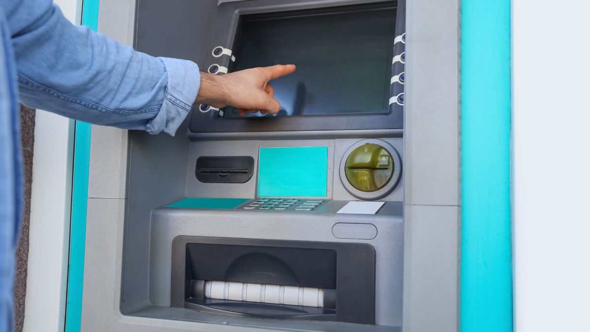 Egy személy mutat a bankautomata érintőképernyőjére, készülve a tranzakcióra.