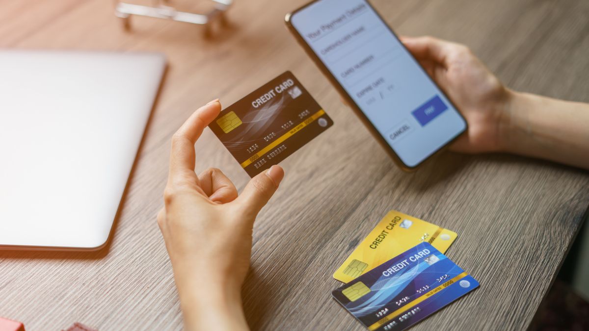 Kézben tartott bankkártya és mobiltelefon, online tranzakcióhoz készülve.