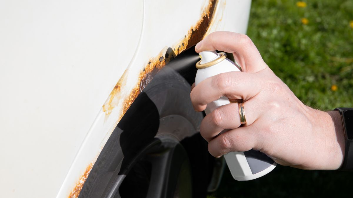 Kéz spray palackkal, rozsdaátalakítót alkalmazva egy fémfelületen.
