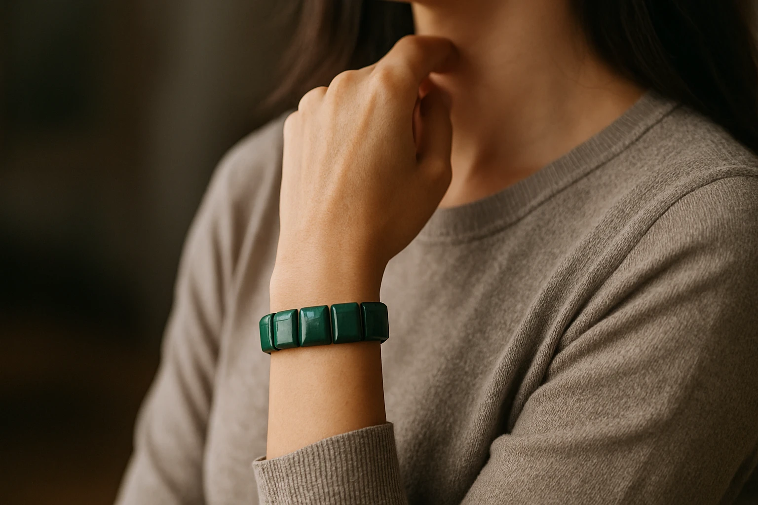 Egy nő karján zöld színű, geometrikus formájú karkötő látható.